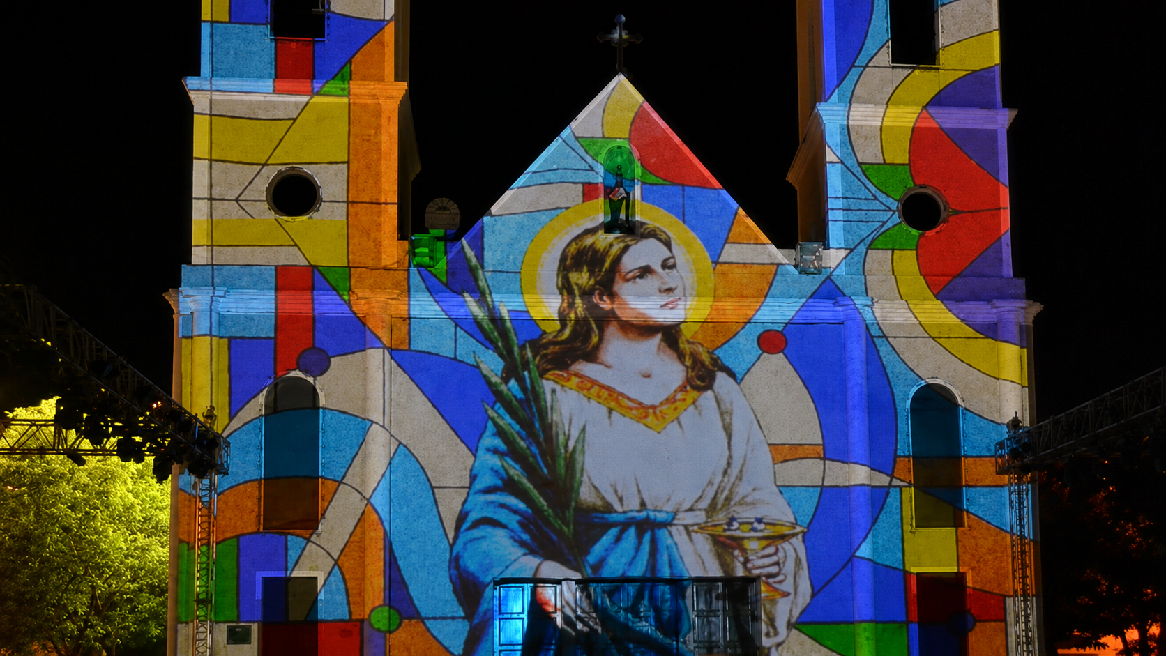 Projeção com formas e cores de vitral sobre fachada com duas torres
